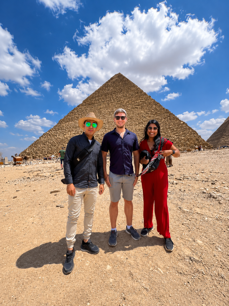 Tourists enjoying a camel ride in front of the Great Pyramids of Giza during a private half-day tour with an authentic Egyptian lunch."